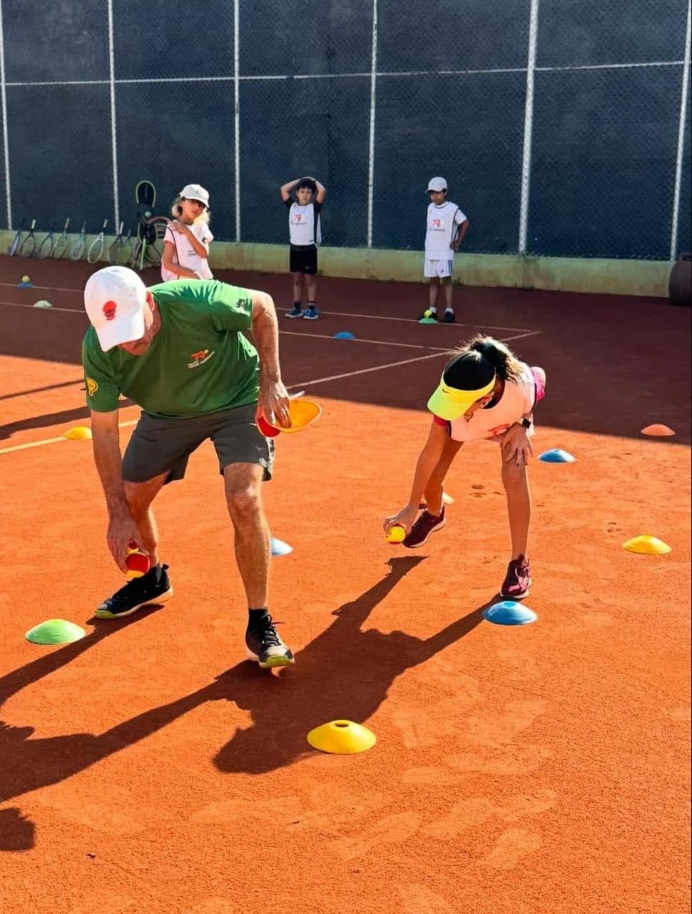 Professor orienta uma aluna em exercício com cones